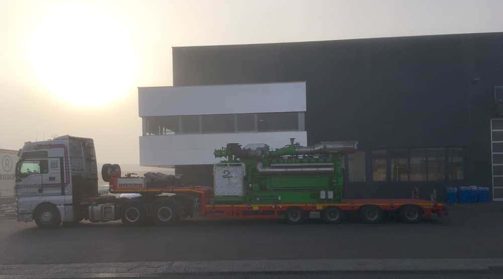 a heavy transport truck carrying a large industrial gas engine